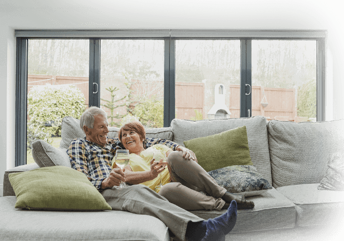 couple sitting on the sofa with aluminium bifold doors in the background
